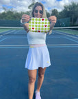 Woman on a tennis court holding a tennis pattern pouch