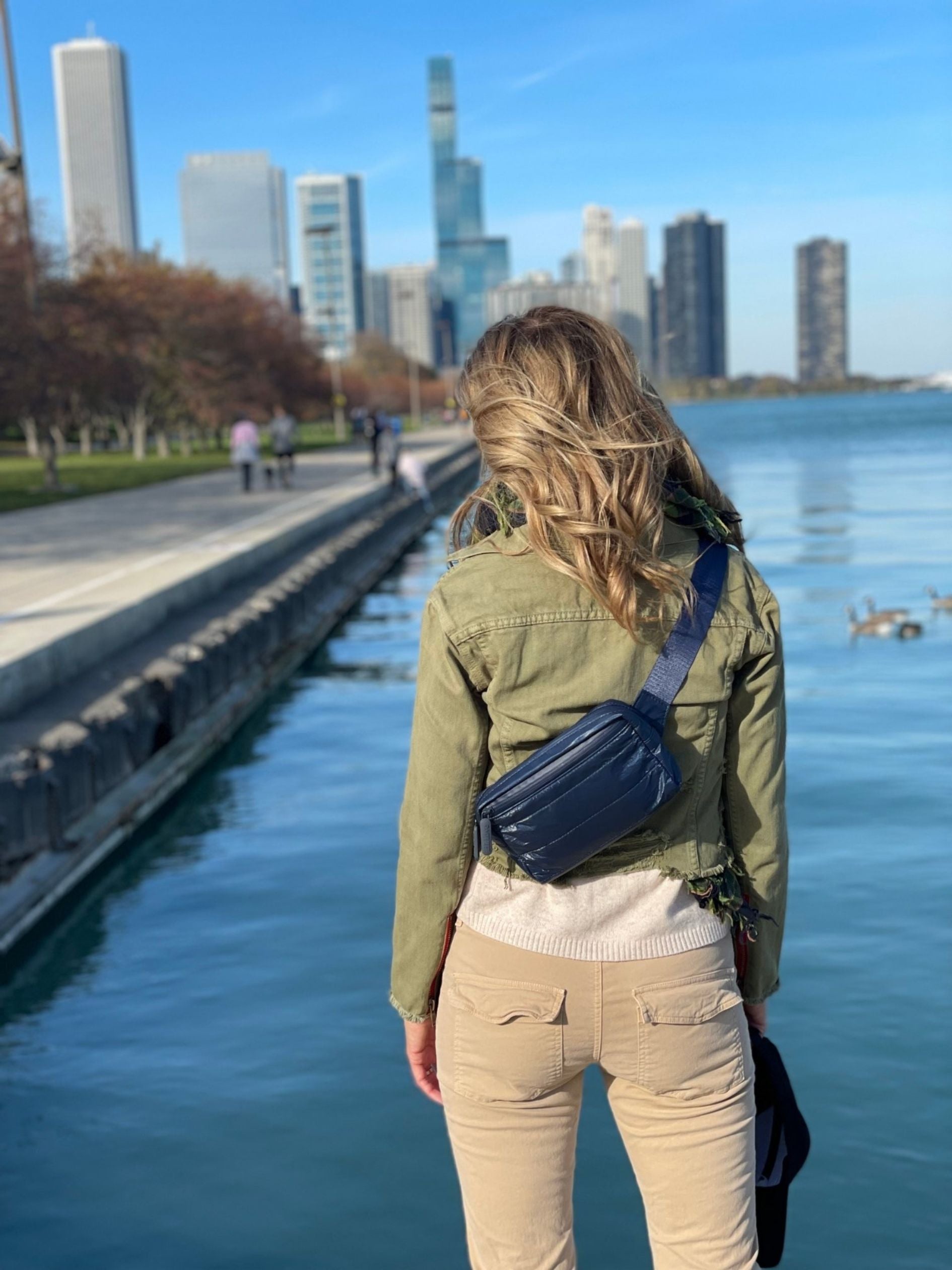 Woman looking at Chicago skyline wearing Puffer Crossbody Fanny Pack Belt Bag in Shimmer Navy Blue