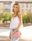 girl wearing white top and jeans with pink purse outdoors