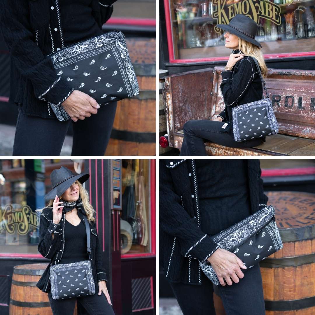 Person holding a black clutch with bandana pattern in front of a bar.
