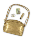 Gold earrings, twenty dollar bill, and lipstick coming out of gold mini puffer clutch with gold chain 