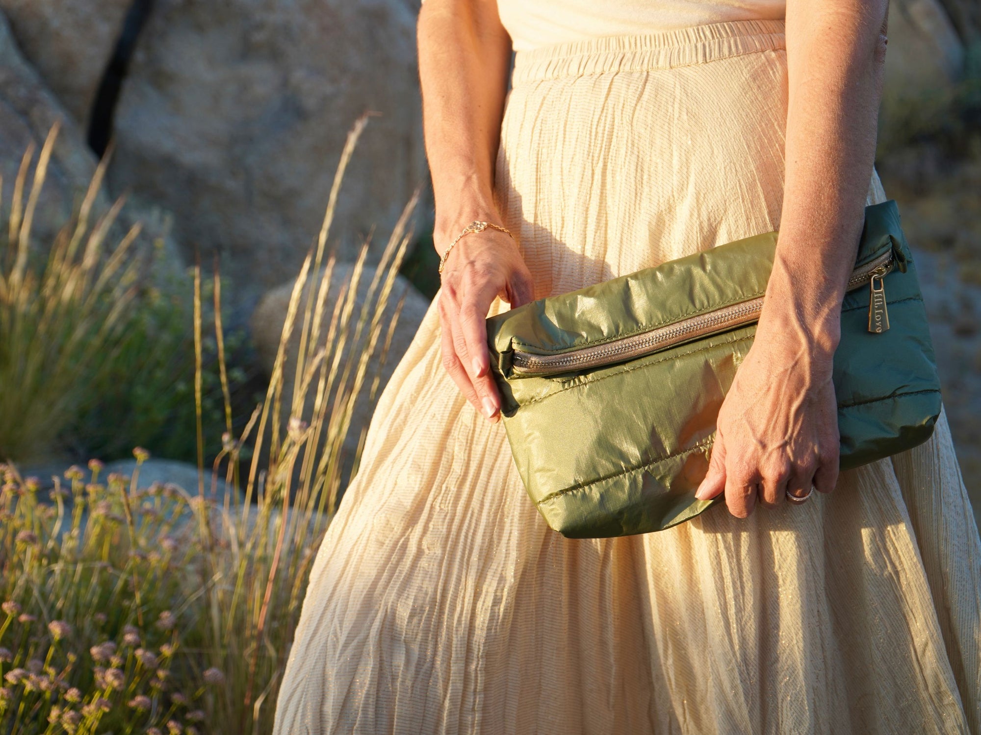 Woman dressed in cream wearing fold over clutch purse in army green with gold zipper