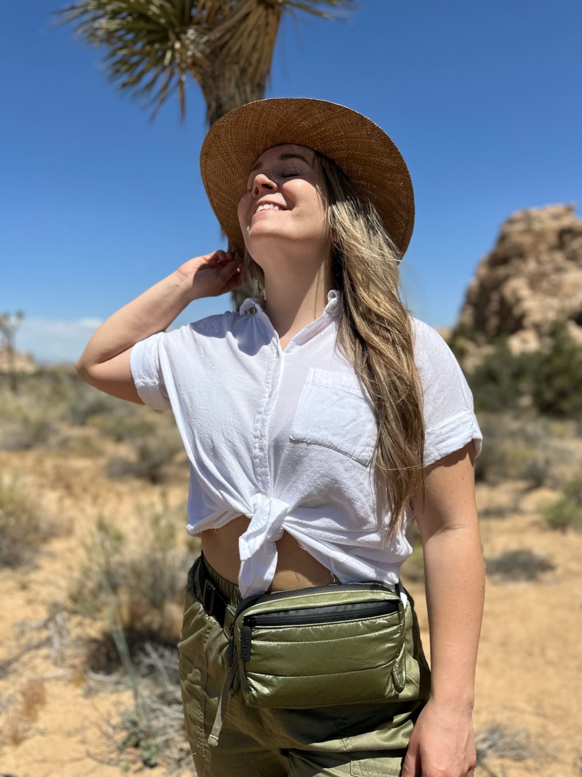 Woman in desert wearing Puffer Crossbody Fanny Pack Belt Bag in Shimmer Olive Green