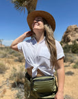Woman in desert wearing Puffer Crossbody Fanny Pack Belt Bag in Shimmer Olive Green