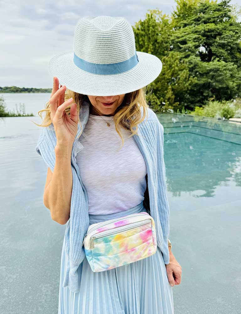 Woman by water wearing watercolor puffer crossbody fanny pack belt bag