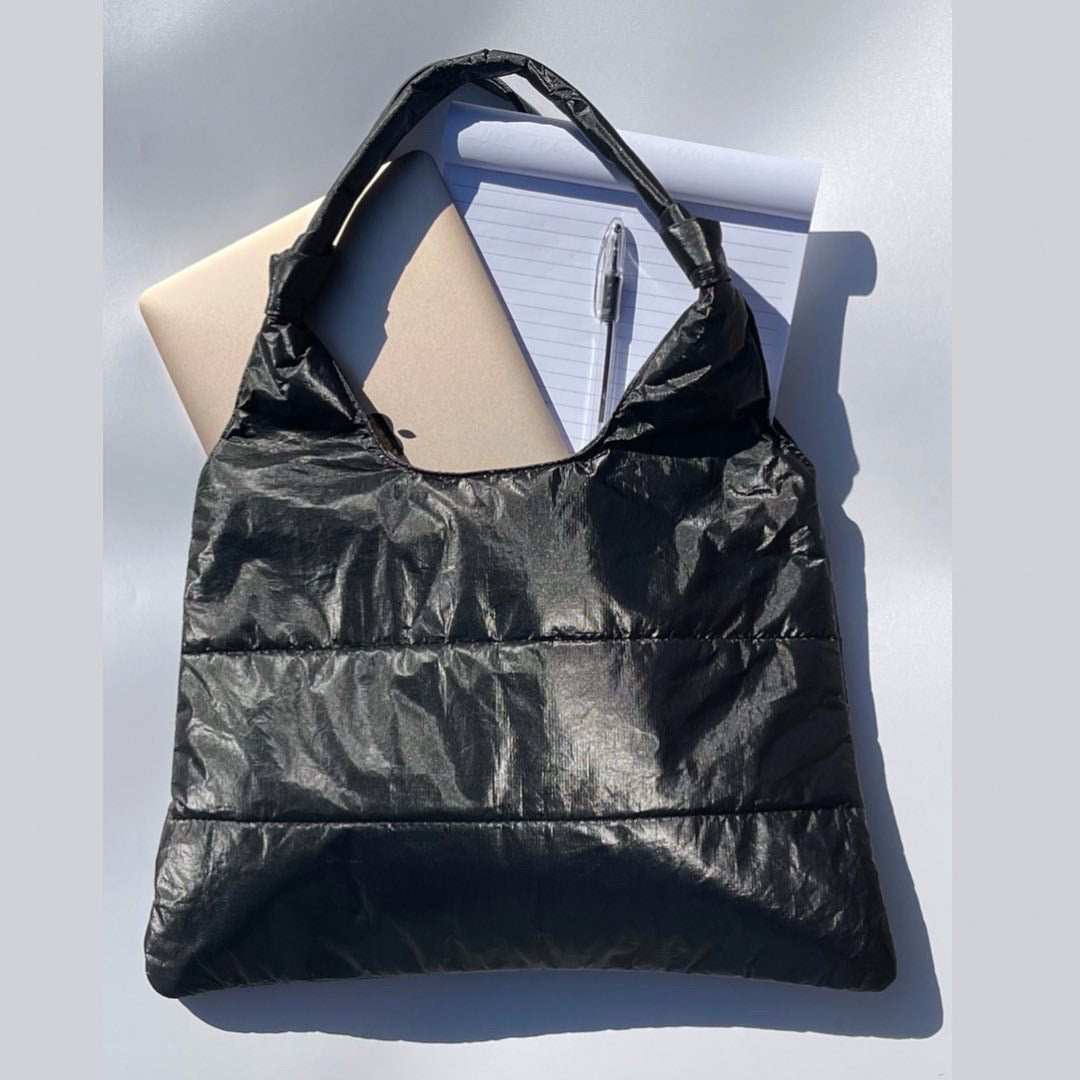Shimmer black puffer tote bag with laptop, notpad, and pen inside
