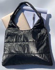 Shimmer black puffer tote bag with gold laptop, notepad, and pen