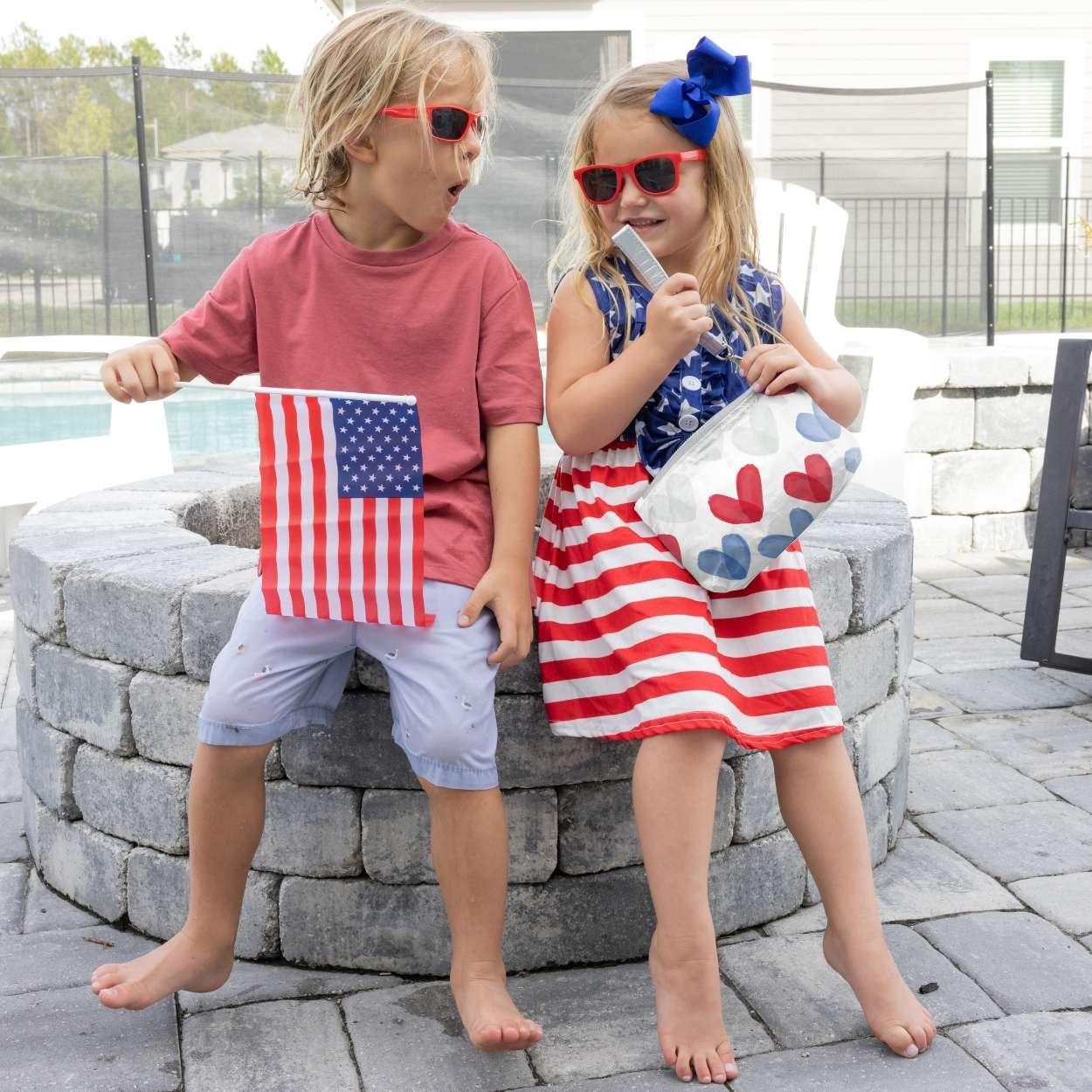 Kids outdoors in red, white, and blue holding a wristlet and American flag 