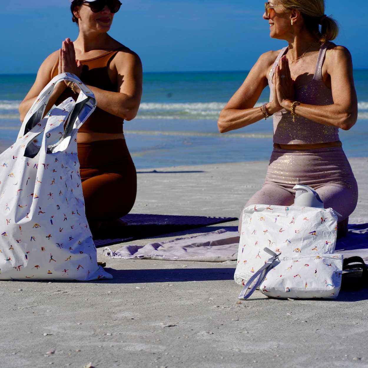 Women doing yoga on the beach with three yoga patterned bags 