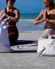 Women doing yoga on the beach with three yoga patterned bags 