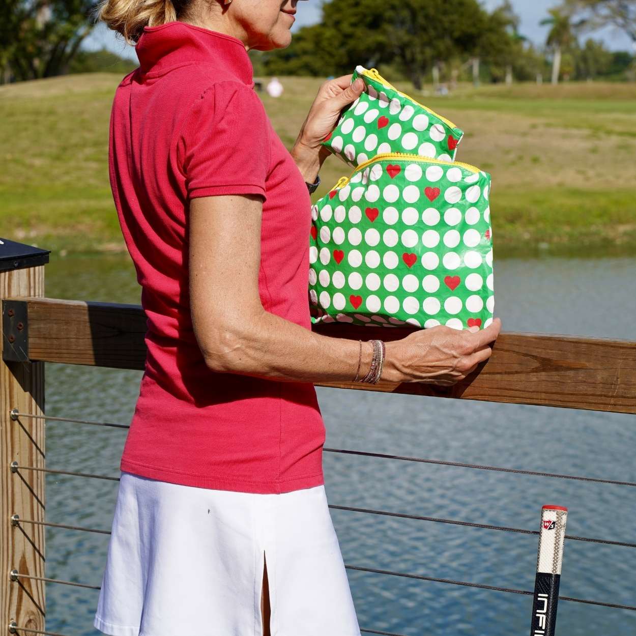 Woman holding green bags with red hearts on a golf course