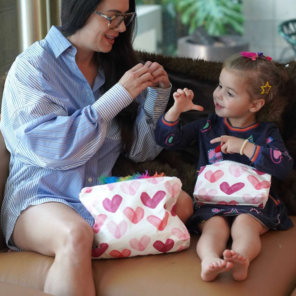 Woman and child sitting on a couch with heart-patterned bags