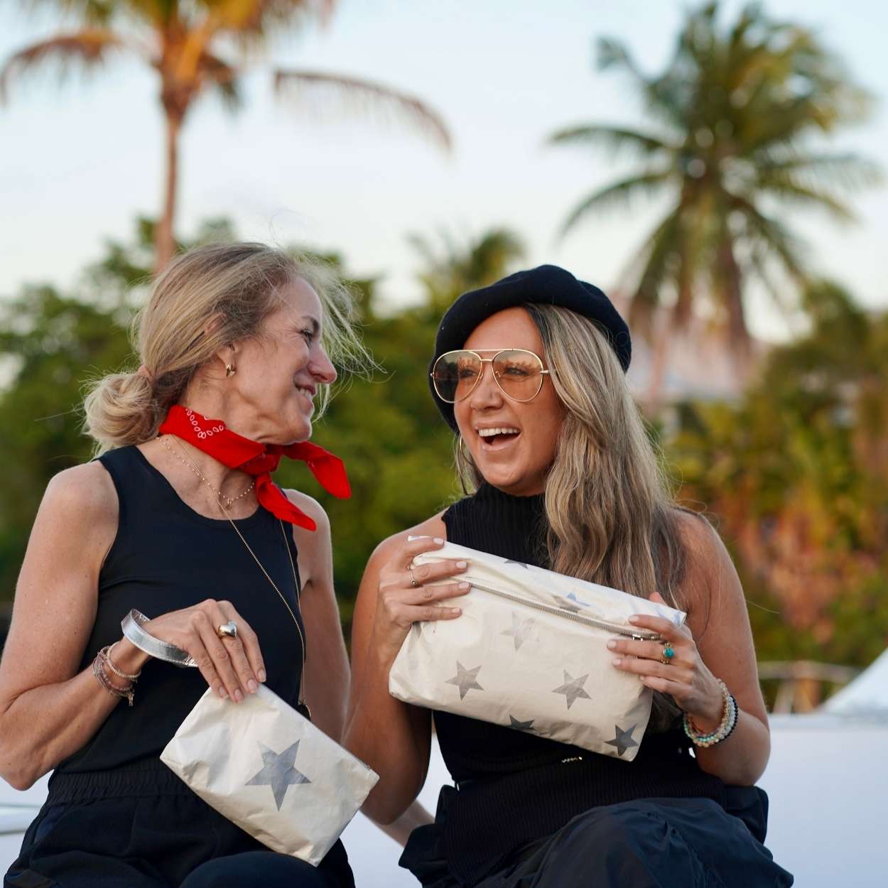 Women wearing all black holing beige pouches with stars on palm tree background 