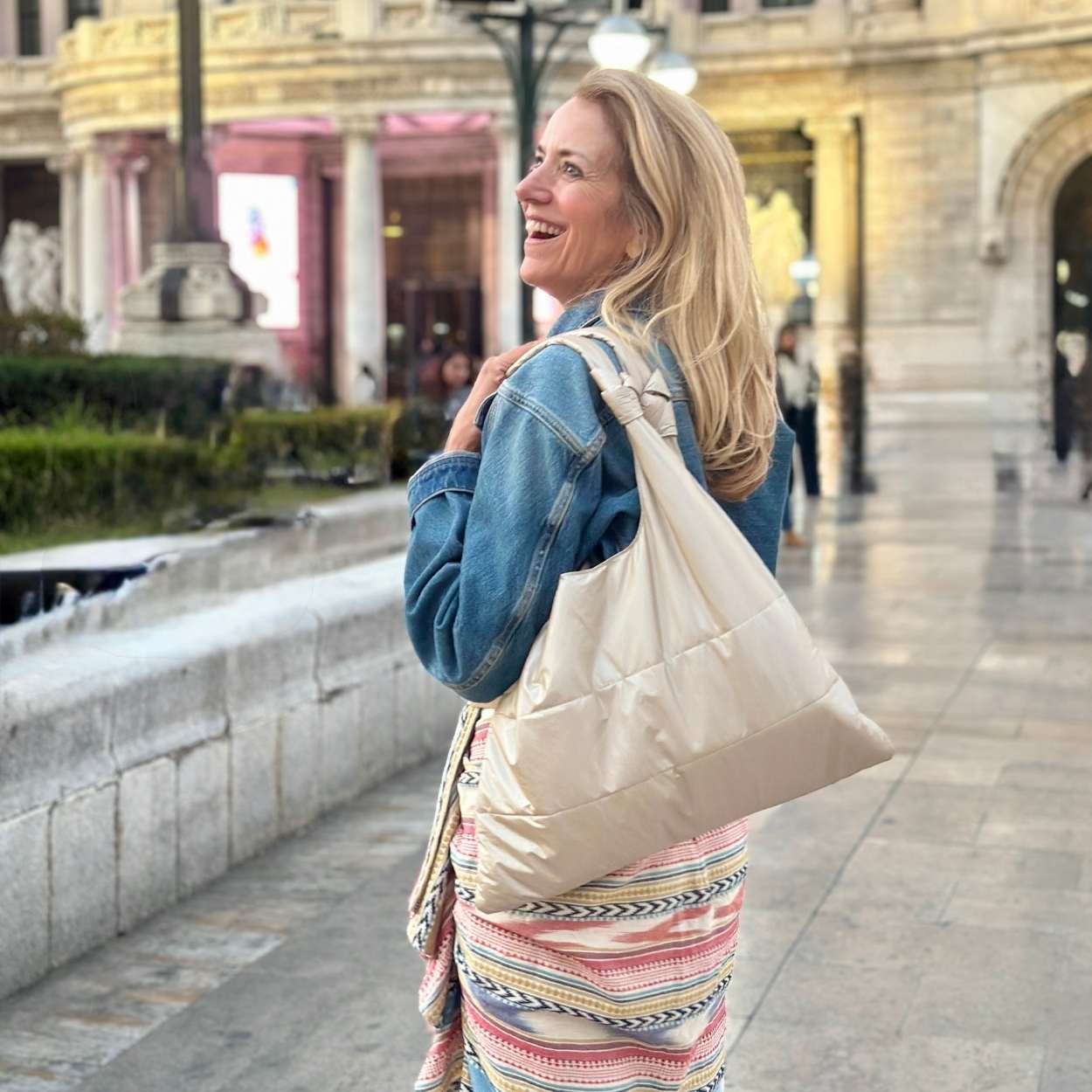 Woman with a beige tote bag walking outdoors in an urban setting