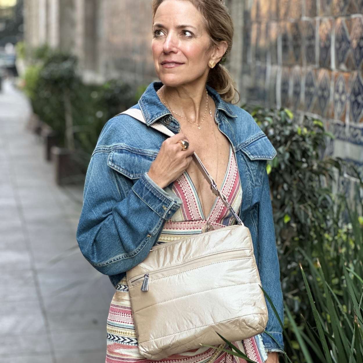 Woman holding a beige handbag on a city street