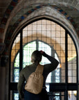 Woman standing inside a chapel wearing shimmer bronze crossbody backpack