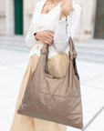 Woman in white sweater and striped pants with shimmer bronze purse over her arm