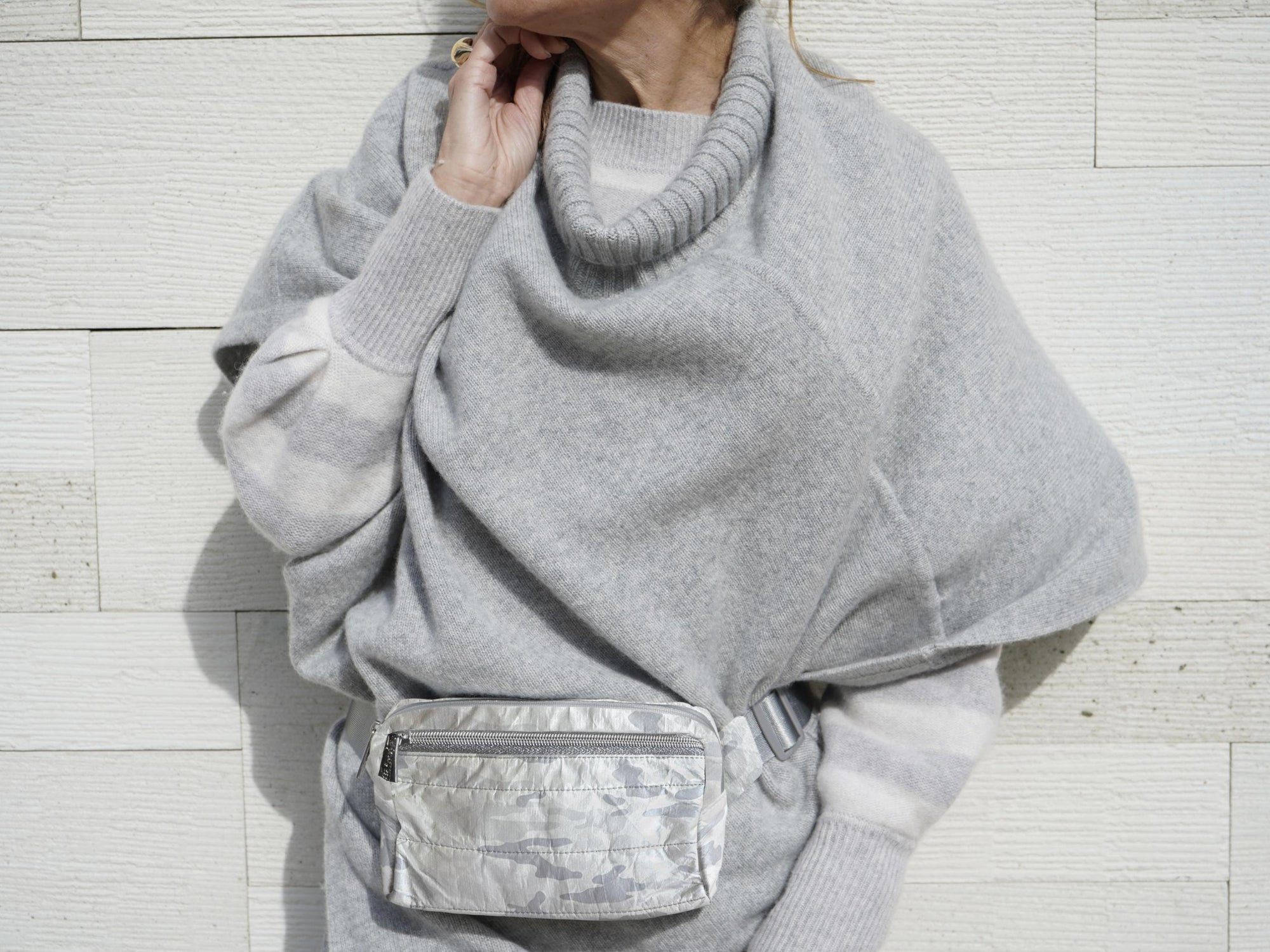 Woman in gray sweater wearing a shimmer white and gray camo puffer crossbody fanny pack belt bag