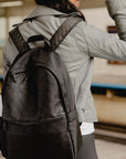 Woman walking through a train station wearing the black signature backpack on her shoulders.