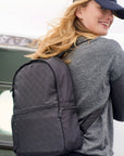 Smiling woman wearing the black signature backpack while boarding a plane.