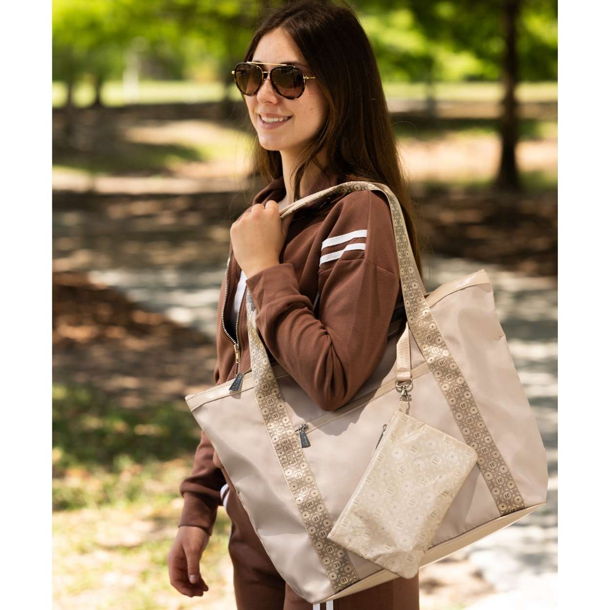 Woman smiling outdoors holding signature travel tote in beige