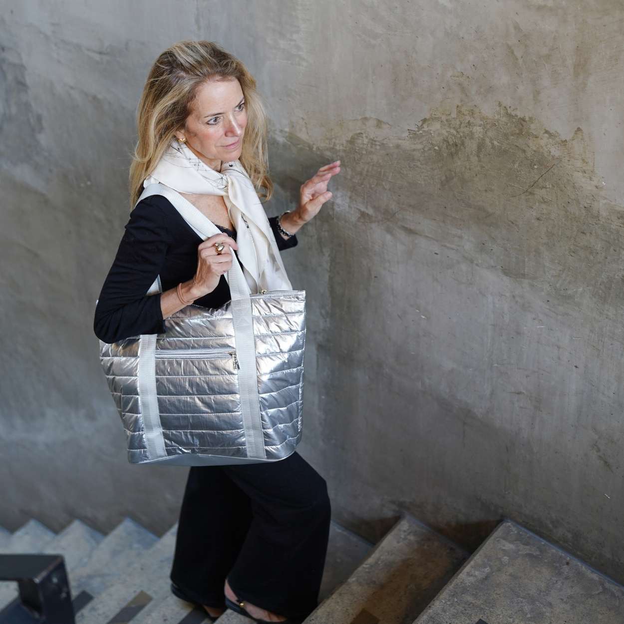 Woman holding a silver quilted bag in an indoor setting