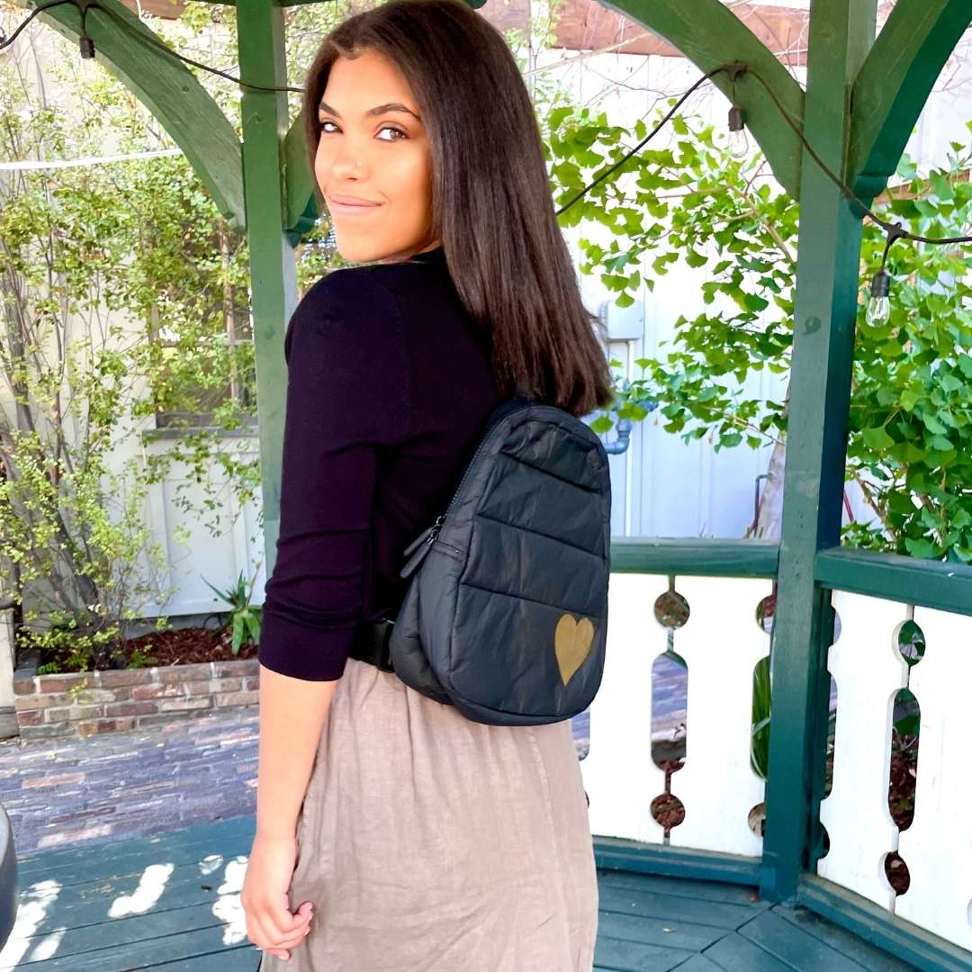 Woman wearing a black gold heart backpack with a heart design outdoors
