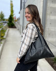 Woman in flannel with a shimmer black handbag over shoulder