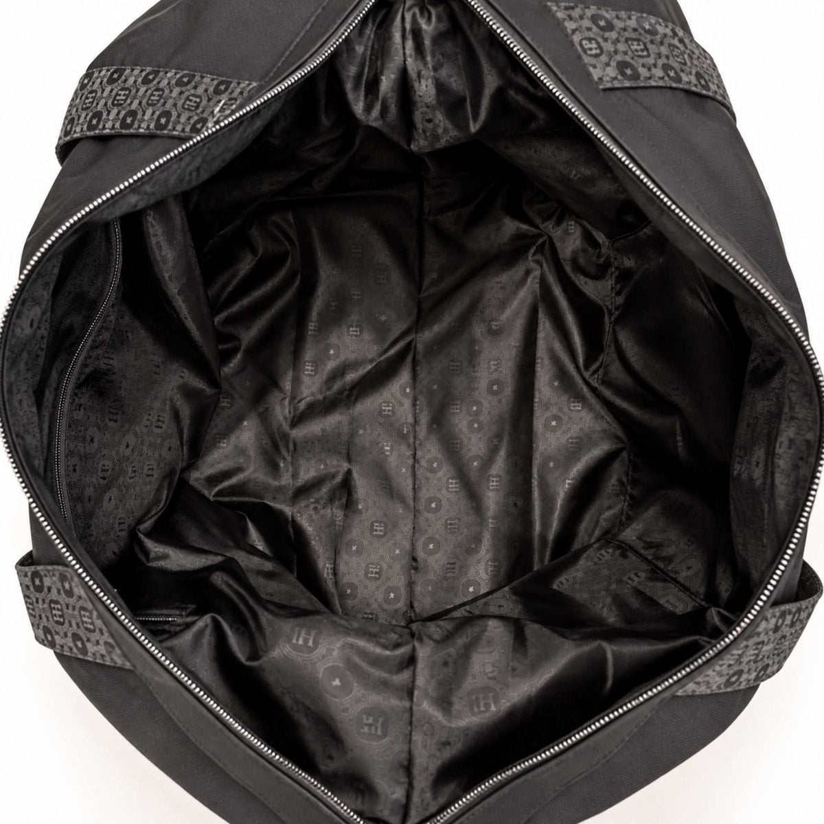 Close-up view of the spacious interior of a black weekender bag, featuring a sleek tonal patterned lining, wide zippered opening, structured sides, and multiple interior details. The soft fabric lining showcases a subtle repeating geometric and monogram-inspired pattern throughout the main compartment and side panels.