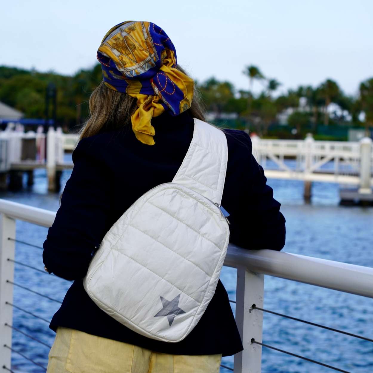 Person with a white bag and colorful headscarf by a waterfront