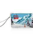 Red Gondola Zip Wristlet featuring a snowy mountain landscape with a bright red gondola, silver zipper, and removable silver wrist strap on a white background.