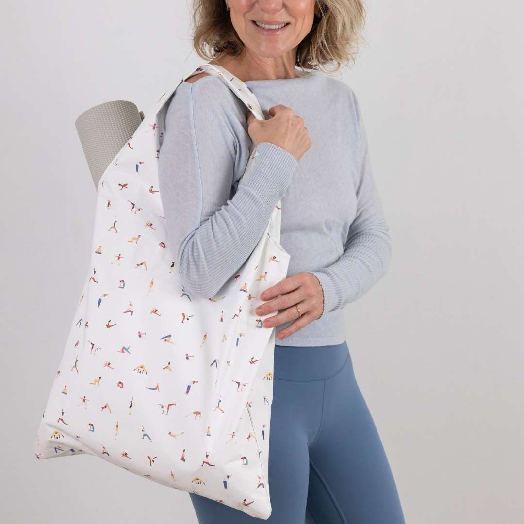 Woman holding a white tote bag with colorful patterns against a plain background