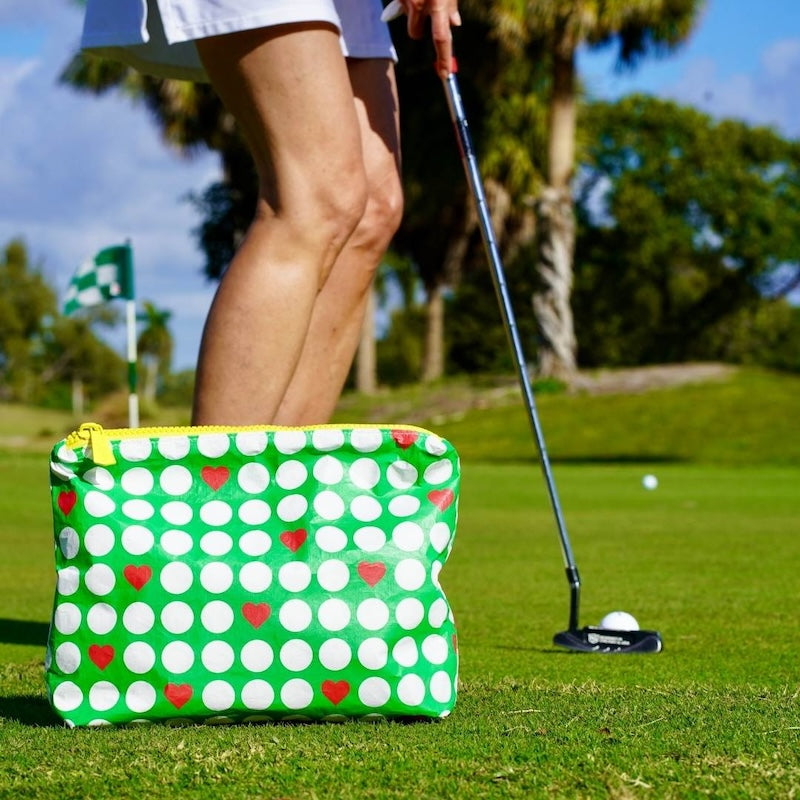 Green pouch with red hearts and golf balls on a golf course