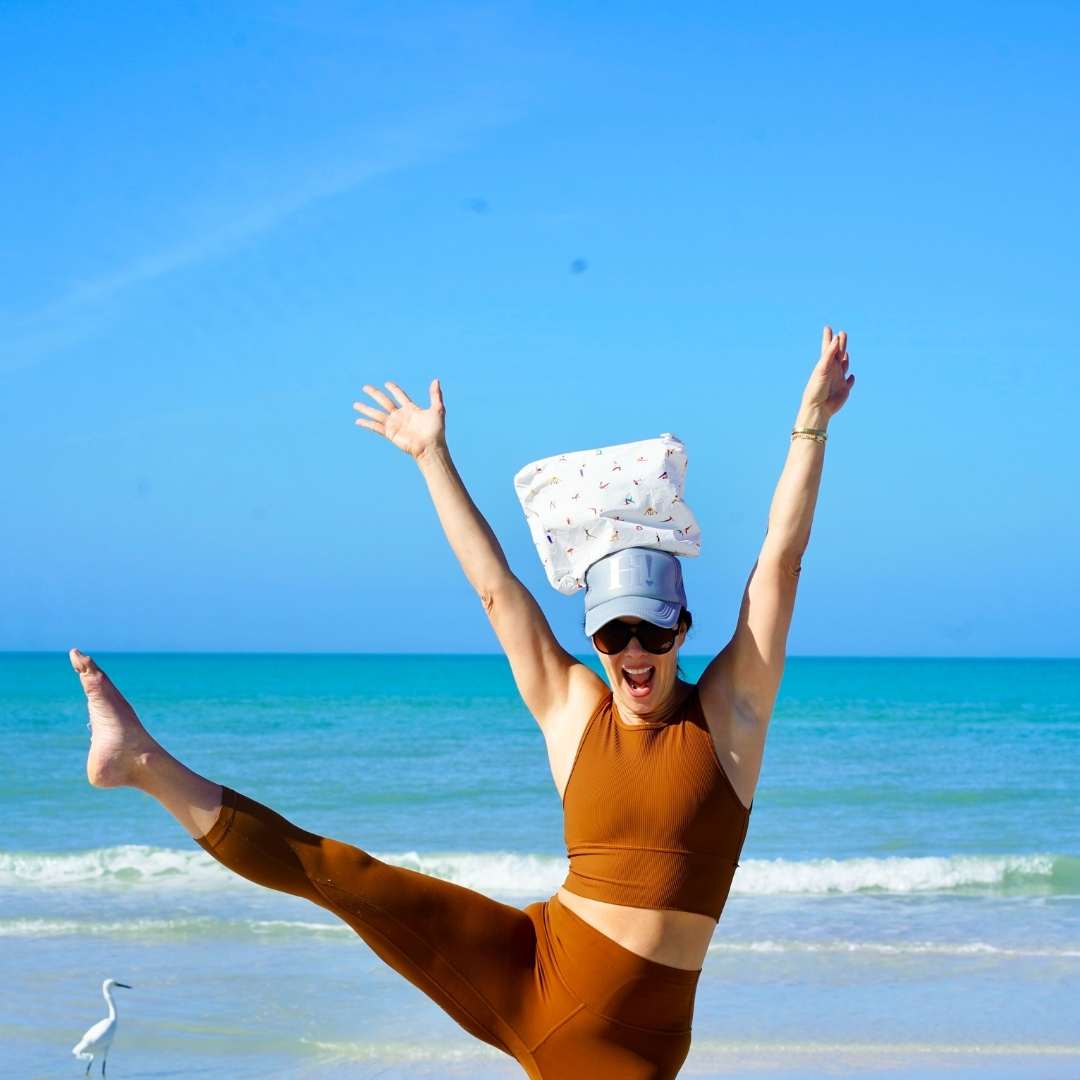 Person in brown athletic wear with a yoga print zipper pouch on their head at the beach