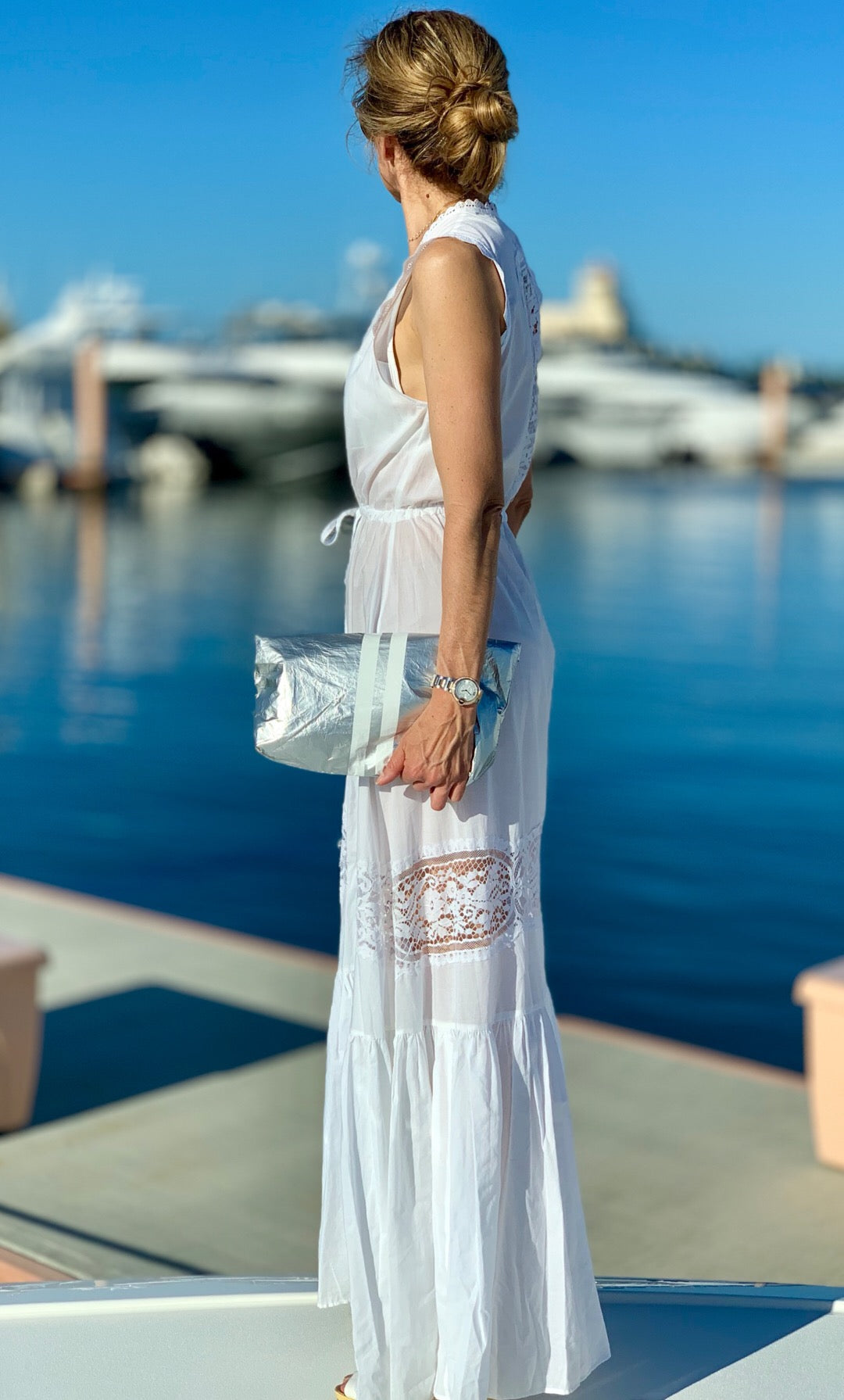 Woman carrying a silver stripe pouch used as a fold over clutch by the water.