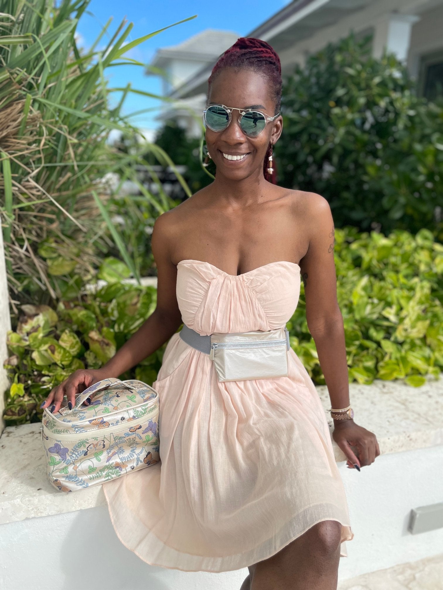 Woman surrounded by greenery wearing fanny pack and holding lunch box