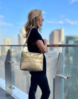 Woman in city wearing a gold puffer purse as shoulder bag