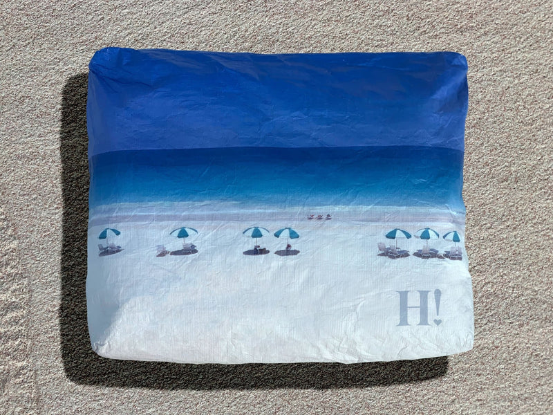 A medium-sized travel pack with a zipper, featuring a Harbour Island beach scene design with blue sky and white sand.