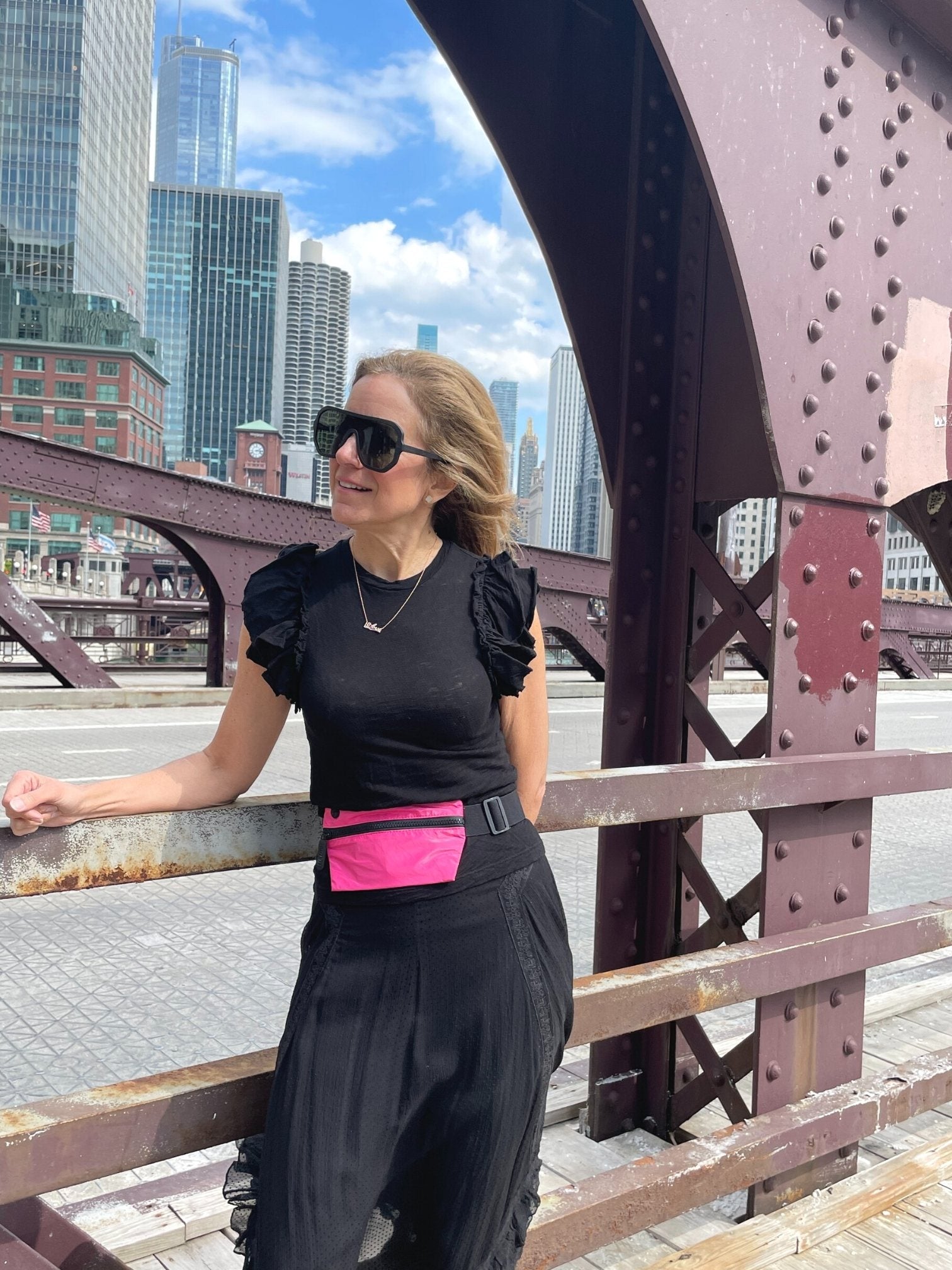 Woman standing on Chicago bridge wearing hot pink fanny pack