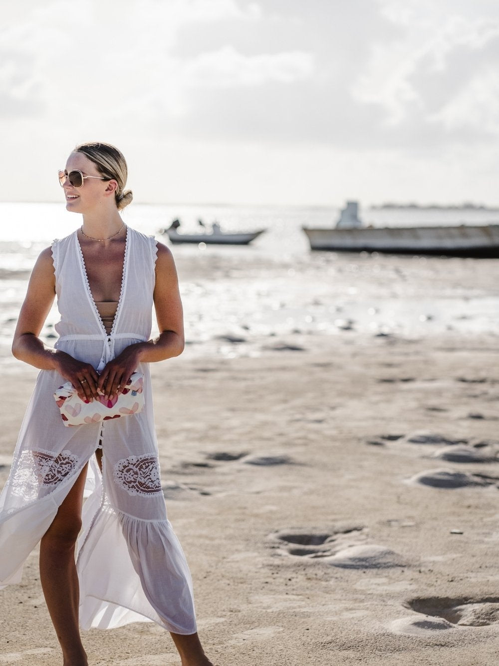Women on beach wearing white dress and sunglasses holding medium zipper pouch in "Language of Love" heart print