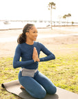 Woman by beach doing yoga wearing fanny pack