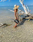 Women walking in shallow water by tree with a zipper pouch in black with silver love printed on it.
