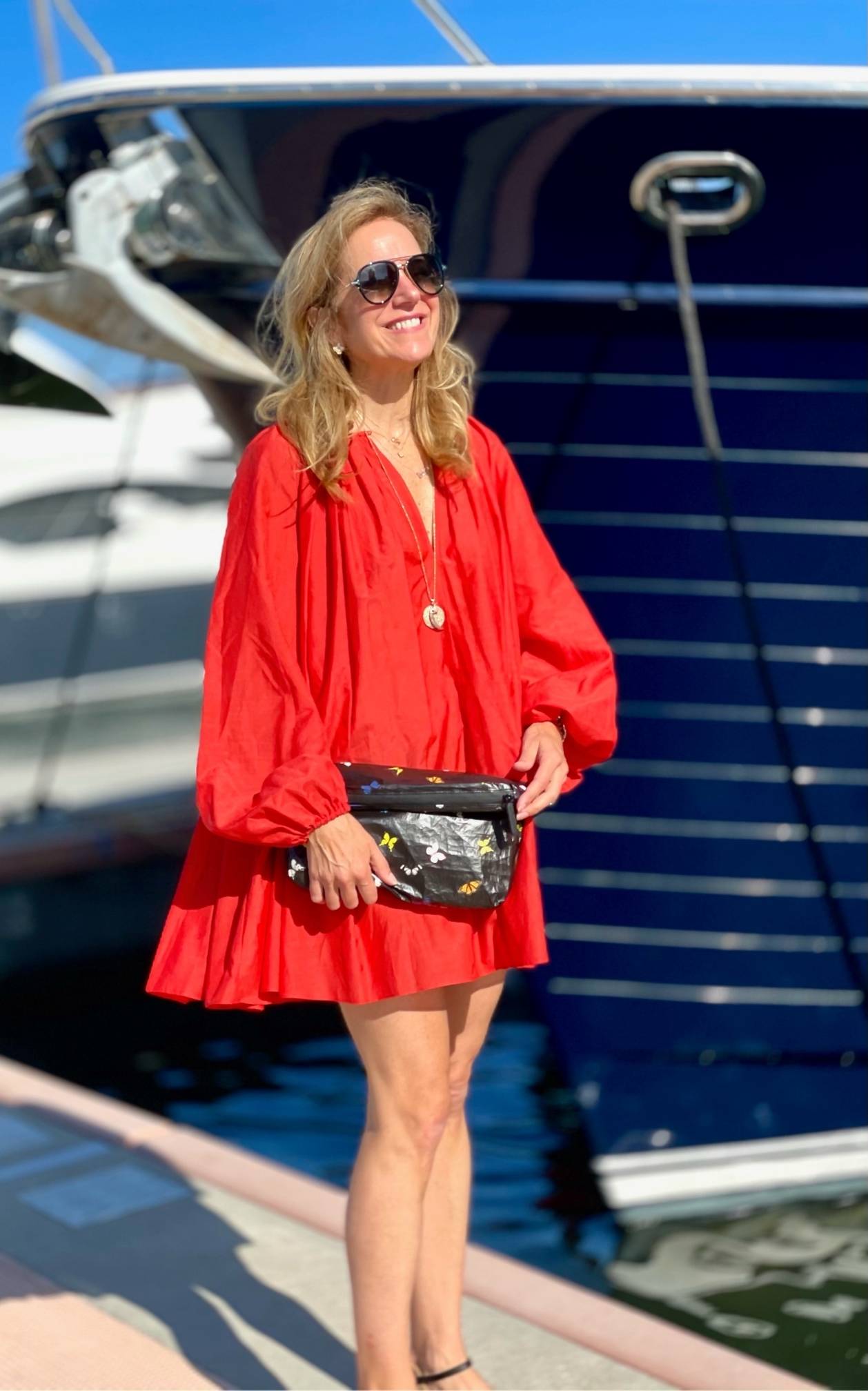 Woman in red dress wearing a black clutch with colorful butterfly print.