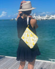 Woman wearing black holding yellow heart bag by the water