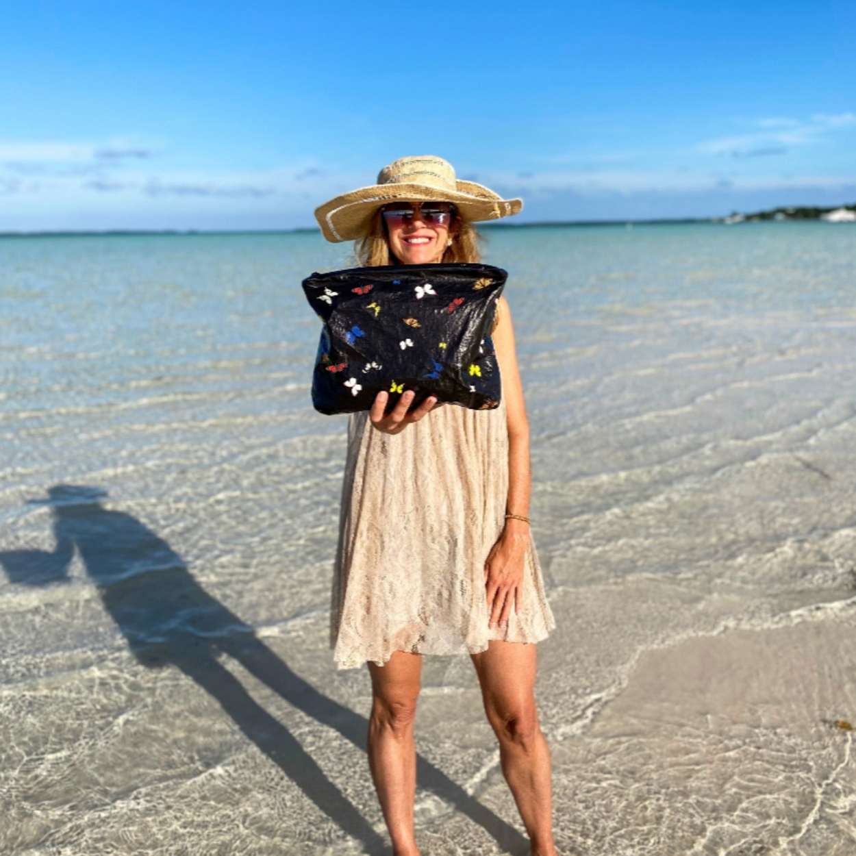Woman holding black pouch with colorful butterflies on the beach