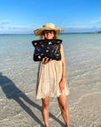 Woman holding black pouch with colorful butterflies on the beach