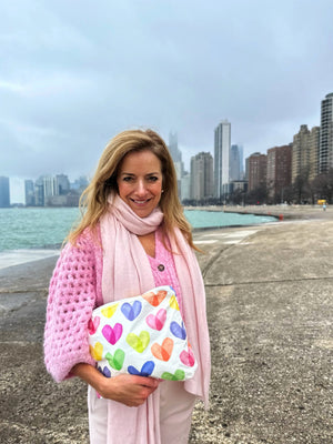 woman in front of Chicago skyline holding rainbow hearts zipper clutch