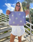 Woman wearing white dress holding purple pouch with stars outdoors