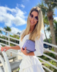 Woman in white dress holding purple clutch outdoors