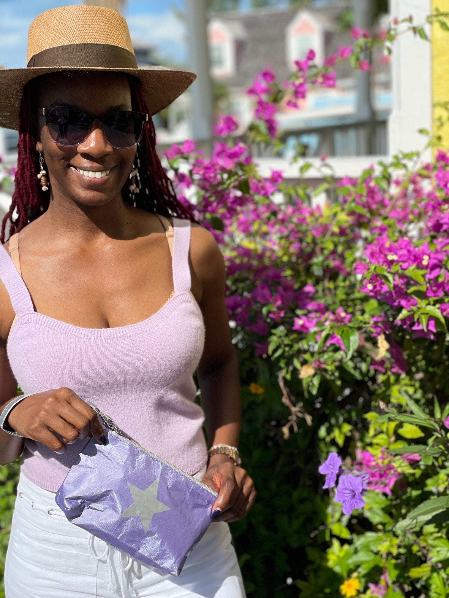 Woman in purple top holding purple pouch with star by flowers